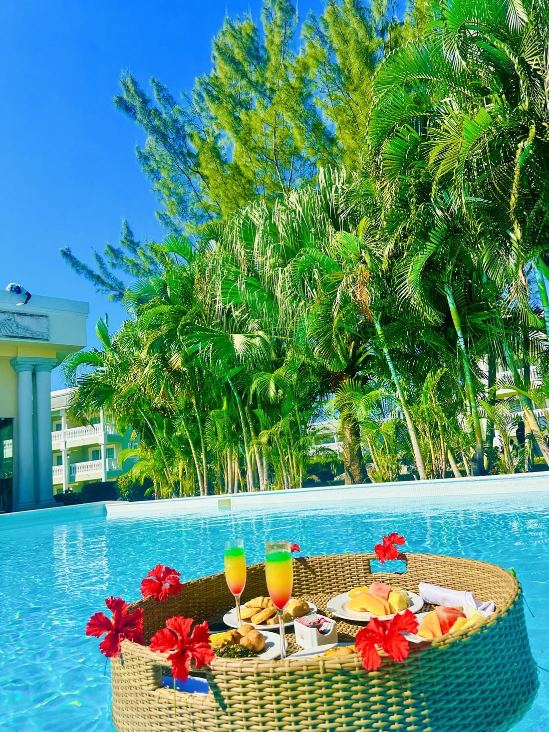Floating breakfast tray with mimosas and hibiscus in a resort pool