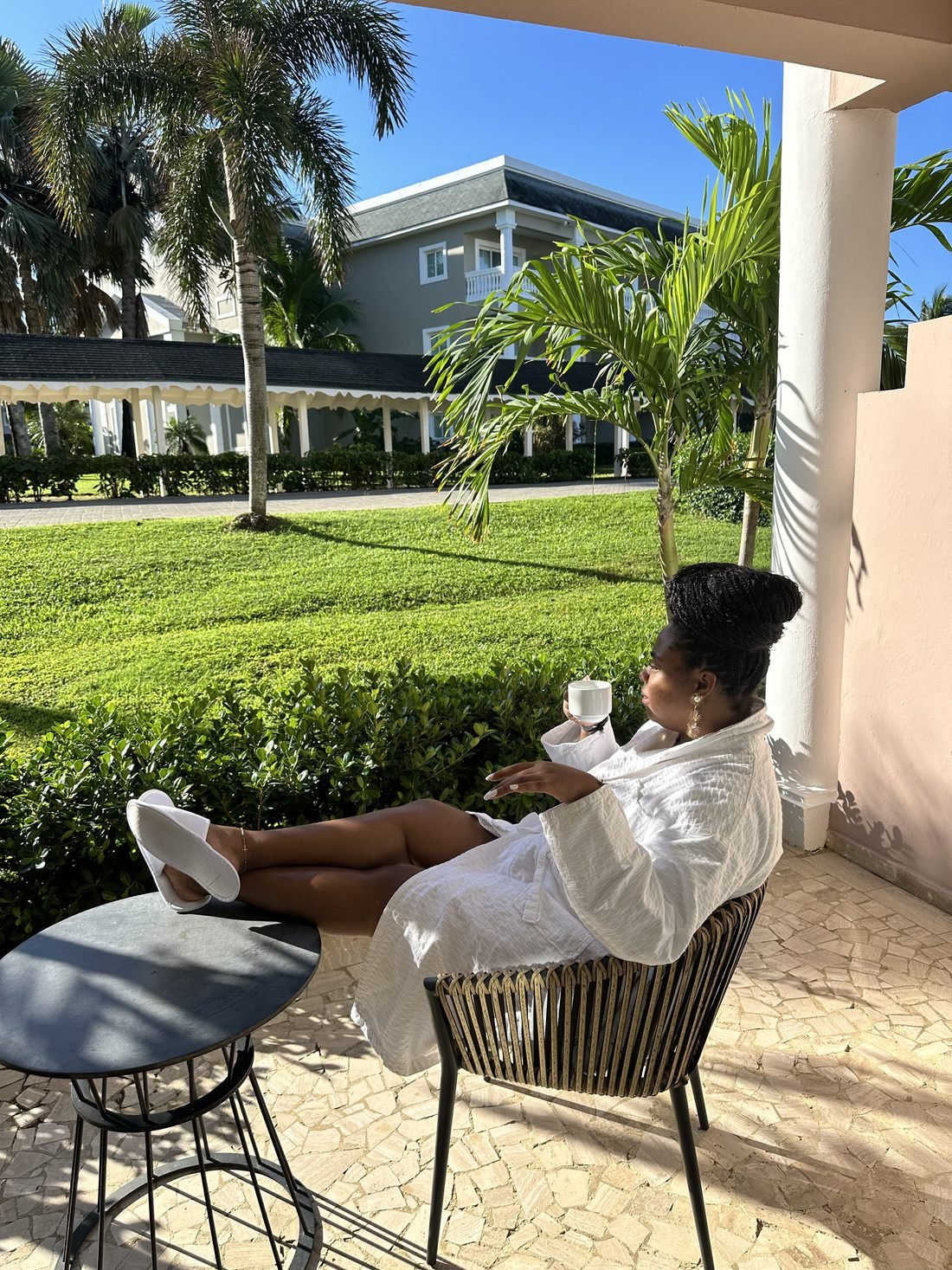 Guest in a white robe with morning coffee on a resort patio